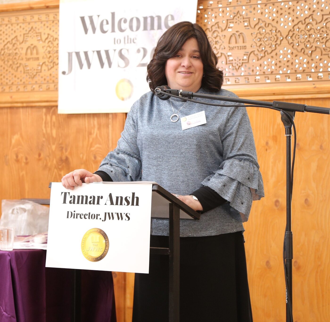Tamar Ansh, Director of JWWS, speaking at a podium at a JWWS gathering